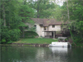 Exterior Back: FOXCLIFF LAKE EAST. Master bedroom left in picture. Open deck right in picture. Lowe level walk out basement with social, wet bar, recreation area. 4th bed w egress window in lower level. Property is a mix of wooded and yard lake frontage.