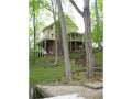 Covered porch @ entry. Timber decks @ south facing wooded lakeside. Terraced walkpaths beautiful for both plants and people. Patio @ water's edge. Mature woods naturally mixes flowering and hardwood species. Ferns and fauna