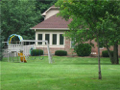 On the s/w corner, year round sunroom captures breeze, lake view, monitor side yard for child's play, all set for creature comfort.