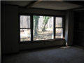 Wood paneled family room. Masonry fireplace with floor hearth, side built in shelving, netural carpet, and mega window wall to view wooded exterior. A mix of pines and hardwoods surround backyard patio