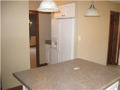 Counter to side of refrigator for loading. Passage to formal dining. Bar stool area under pendant lighting at center island. Powder bath off kitchen/breakfast area. Hard surface flooring from garage, exterior patio, and entry foyer.