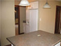 Counter to side of refrigator for loading. Passage to formal dining. Bar stool area under pendant lighting at center island. Powder bath off kitchen/breakfast area. Hard surface flooring from garage, exterior patio, and entry foyer.