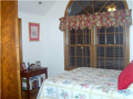 Bedroom 2: Arched window in vaulted ceiling. Large closet. Stained woodwork. Hardwood floor.